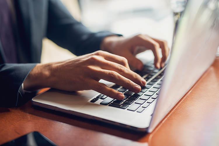 hands typing on a laptop keyboard