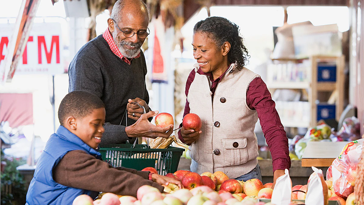 Grandparents and grandson choosing apples at a market.