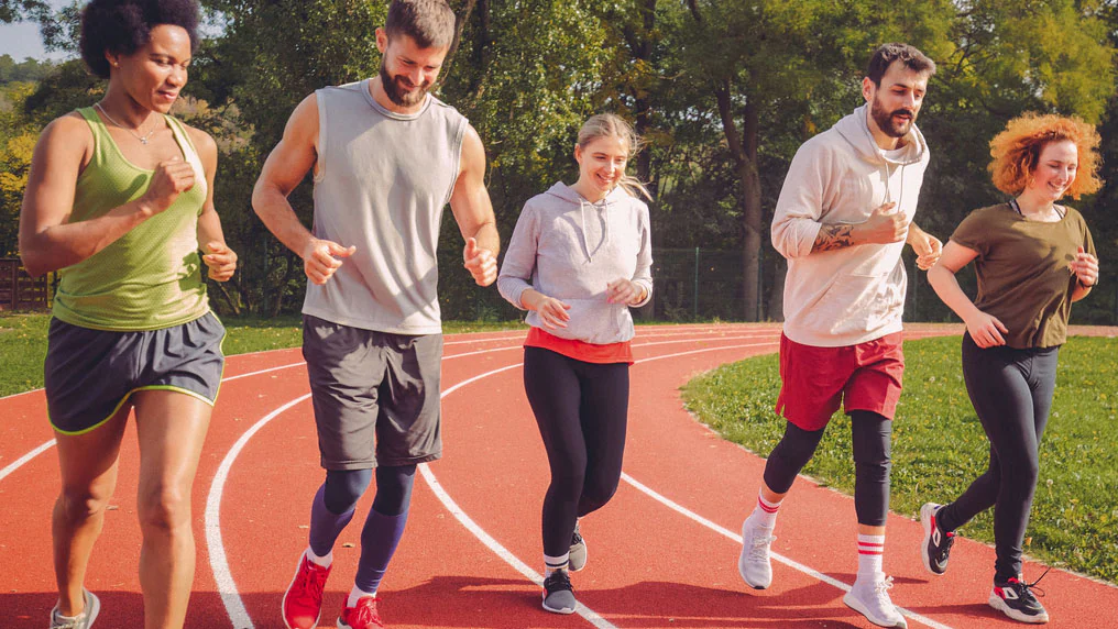 Five adults running on a track