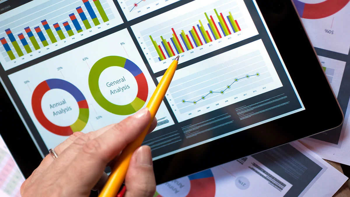 Hand holding pencil up to charts and graphs