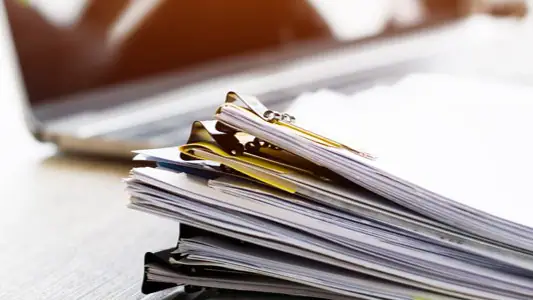 A stack of printed resources and materials on a desk.