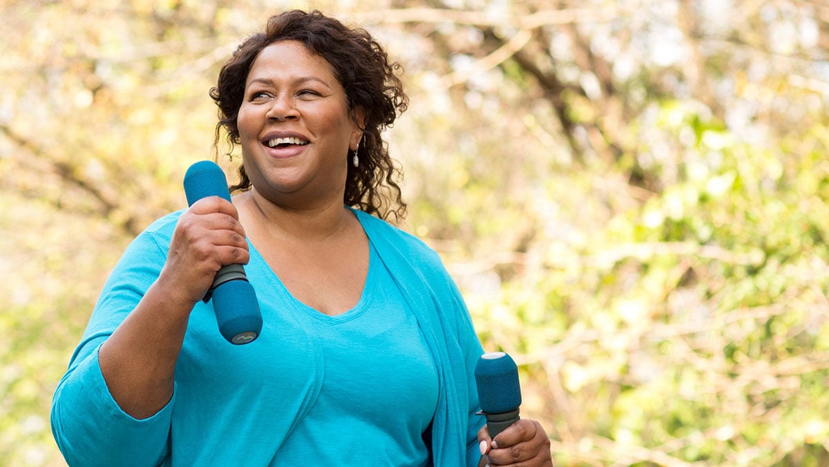 African American woman carrying weights and walking