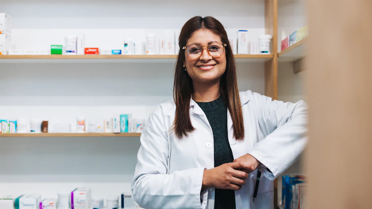 Pharmacist standing in a drug store and looking at the camera.