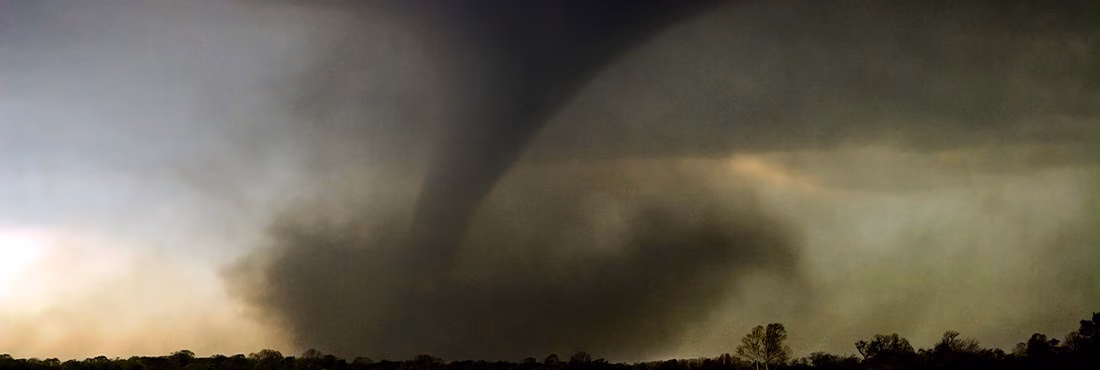 Un gran tornado abre un camino a través de un bosque y arroja escombros al aire. Un gran tornado abre un camino a través de un bosque y arroja escombros al aire.