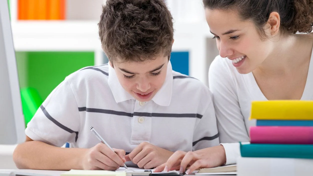 A child is being tutored by a teenager.