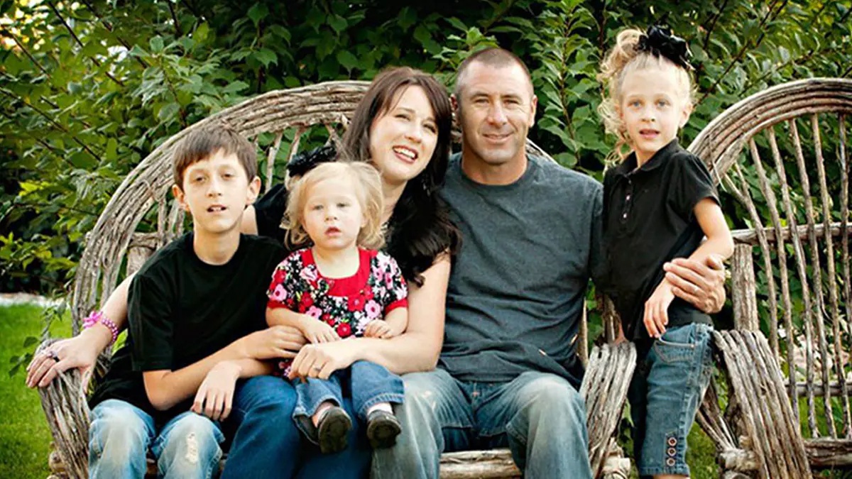 family sitting on bench with all three children that have fxs