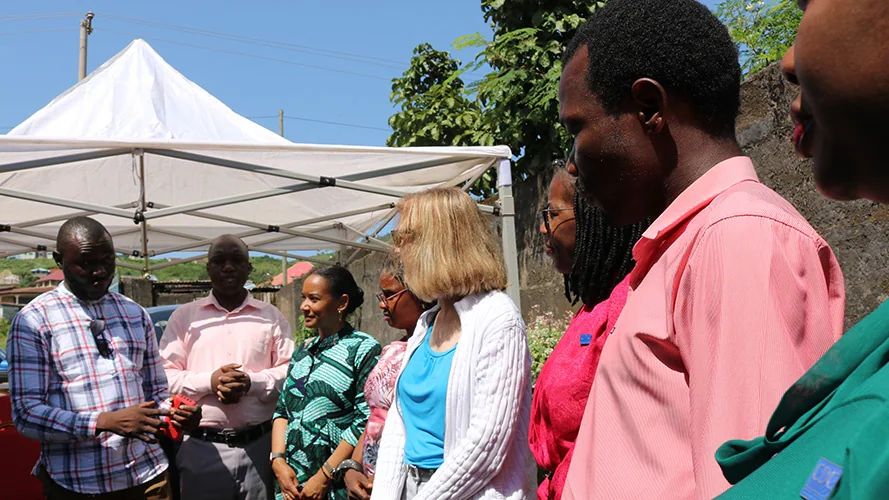 — title missing — A group of health officials gather and talk outside a local school where health workers are holding a vaccine event for students.