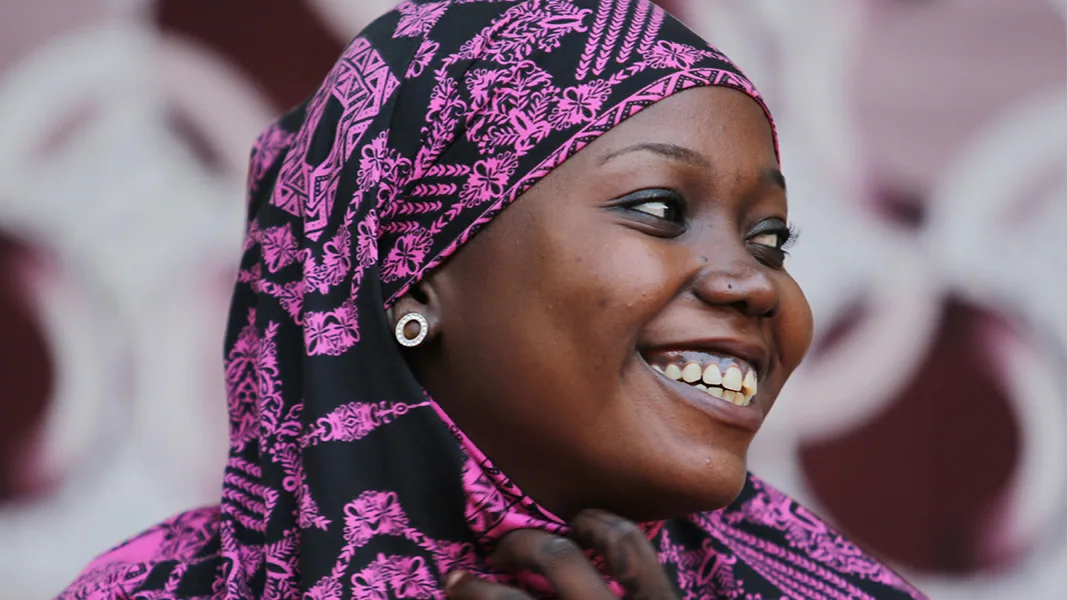 A woman in a headdress sits smiling.