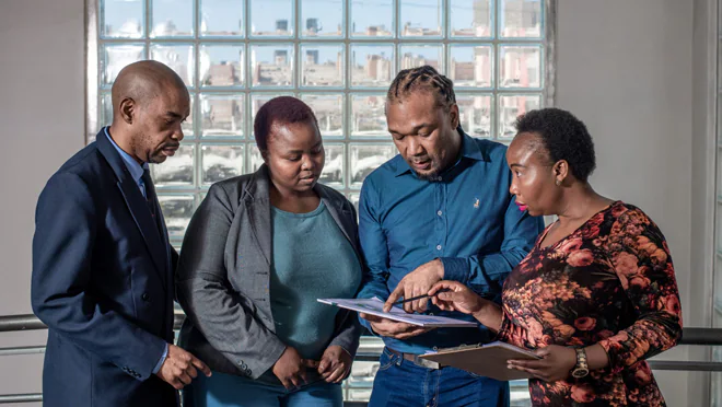 A group of people standing looking at documents.