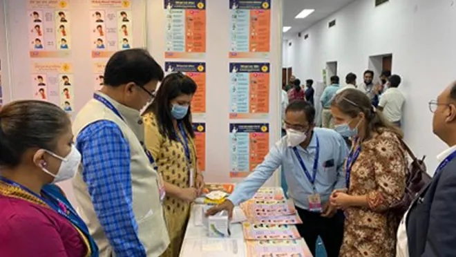 Individuals stand around a table reviewing TB factsheets.