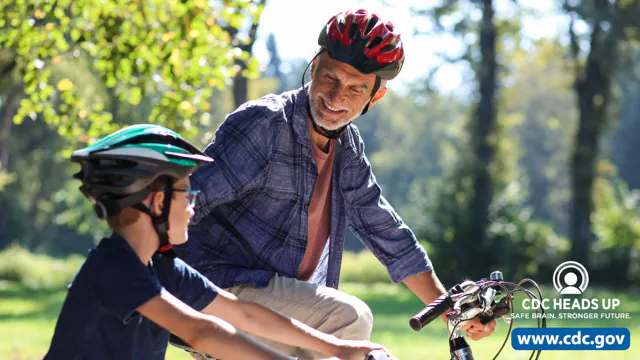 Father and son riding bikes and wearing helmets.