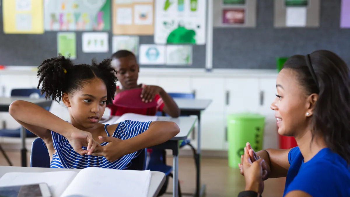 Teacher and child talking in sign language at elementary school