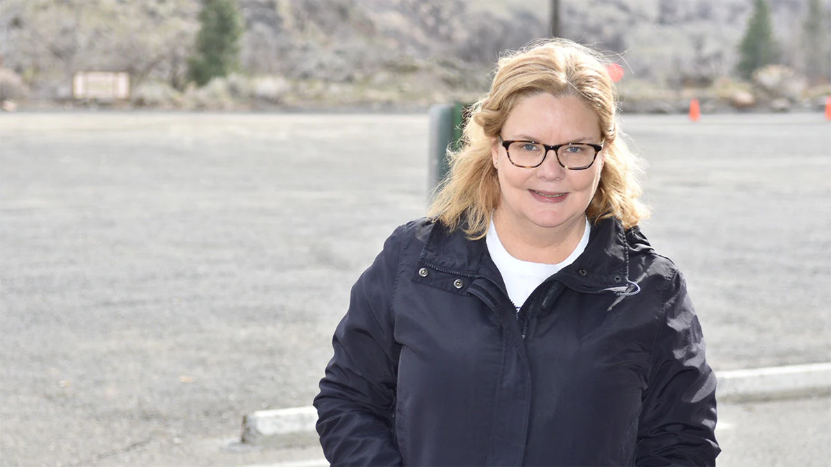 Smiling woman standing in front of a mountain