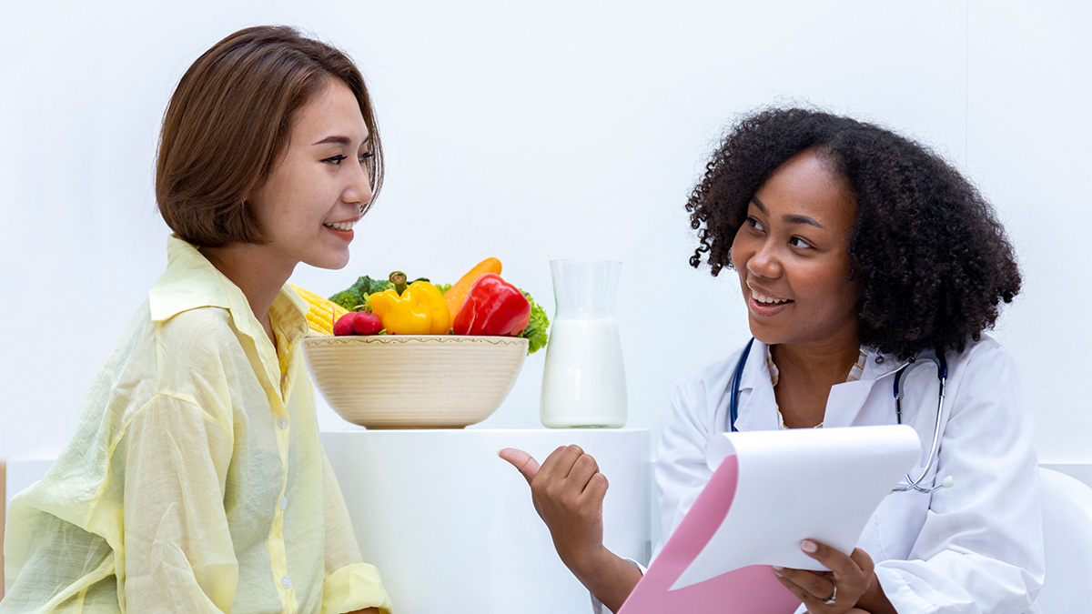 A doctor sitting with a patient and showing her information on a clipboard