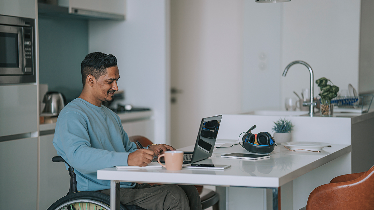 Man in a wheelchair sitting at a computer researching hepatitis basics