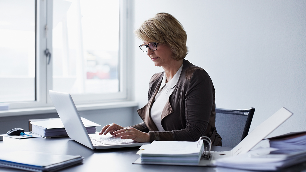 Business professional sitting at their desk reviewing scientific information on their laptop