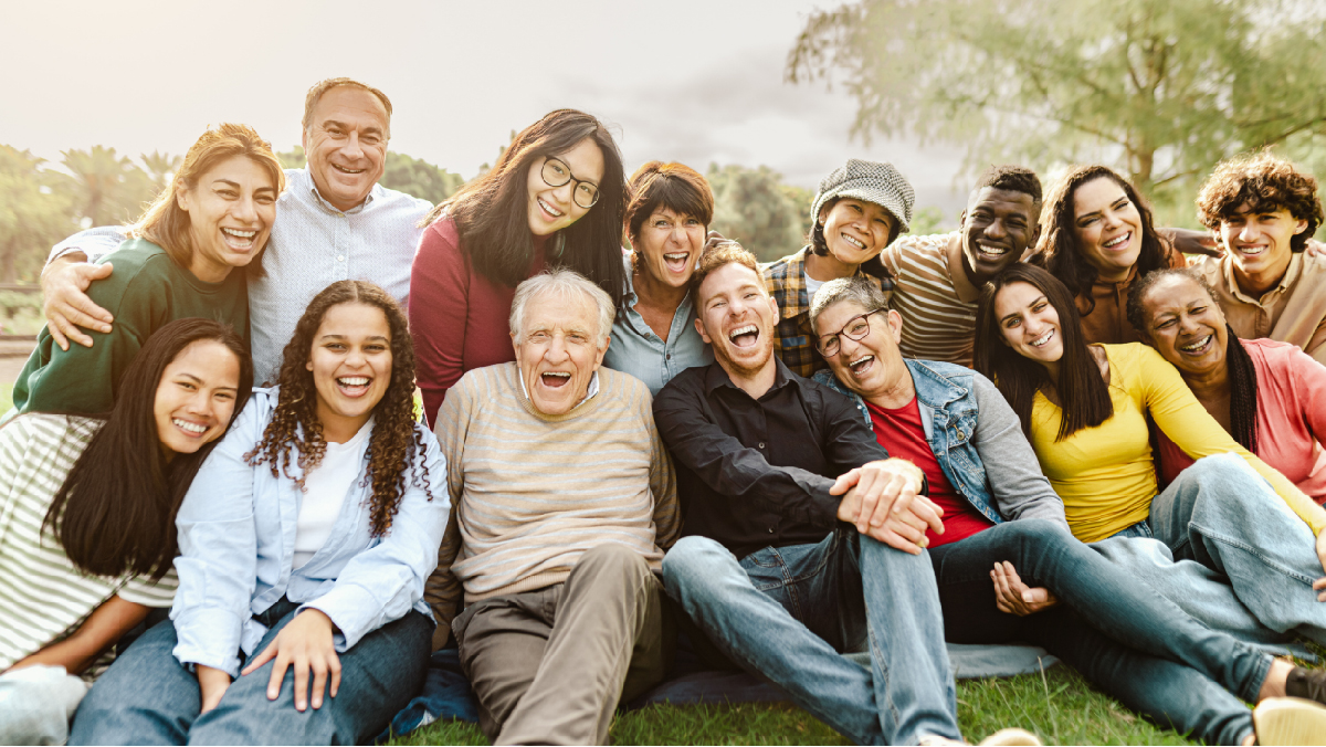 Group of people sitting together on the grass, smiling.