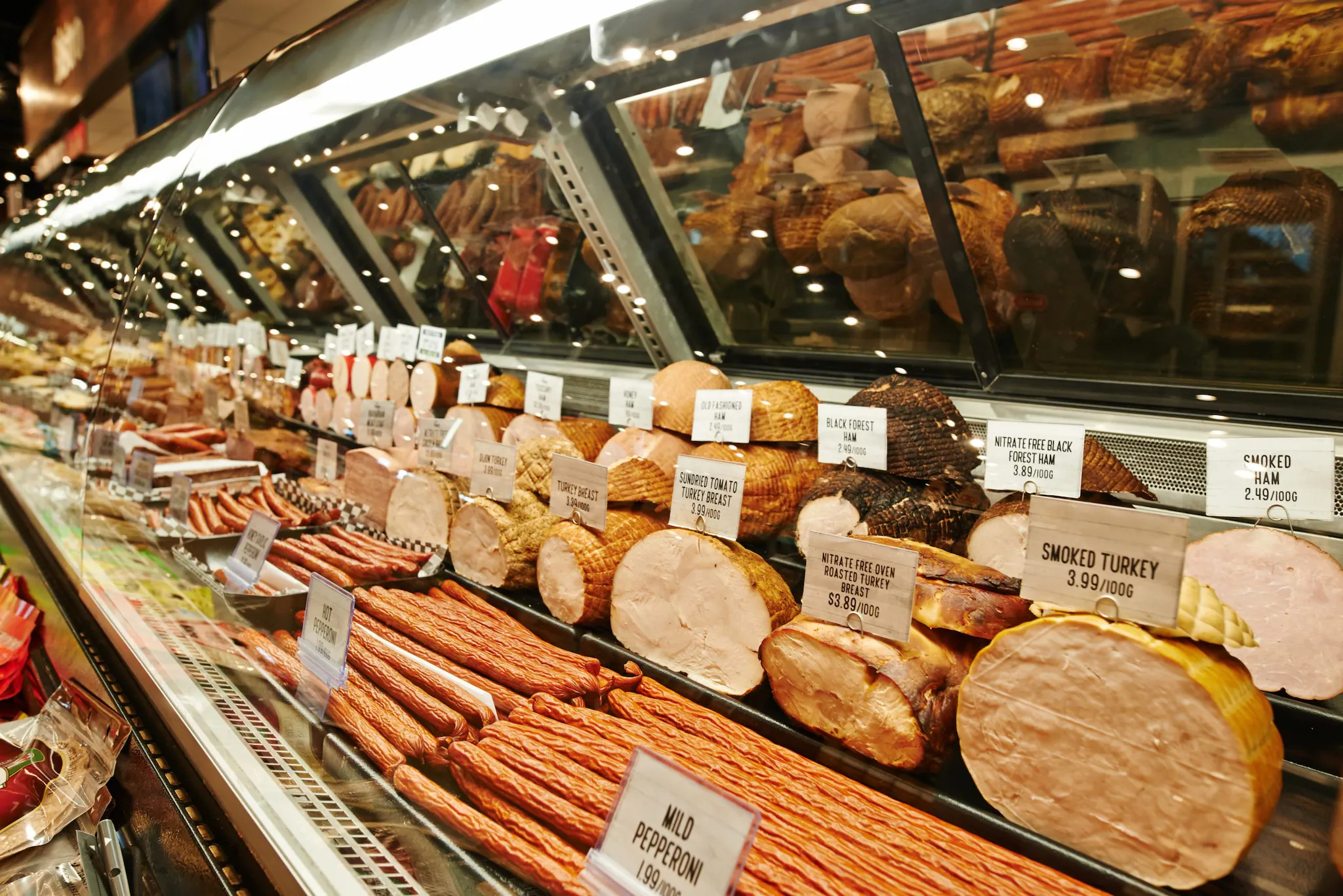 A deli market depicting different types of deli meat on display for slicing.