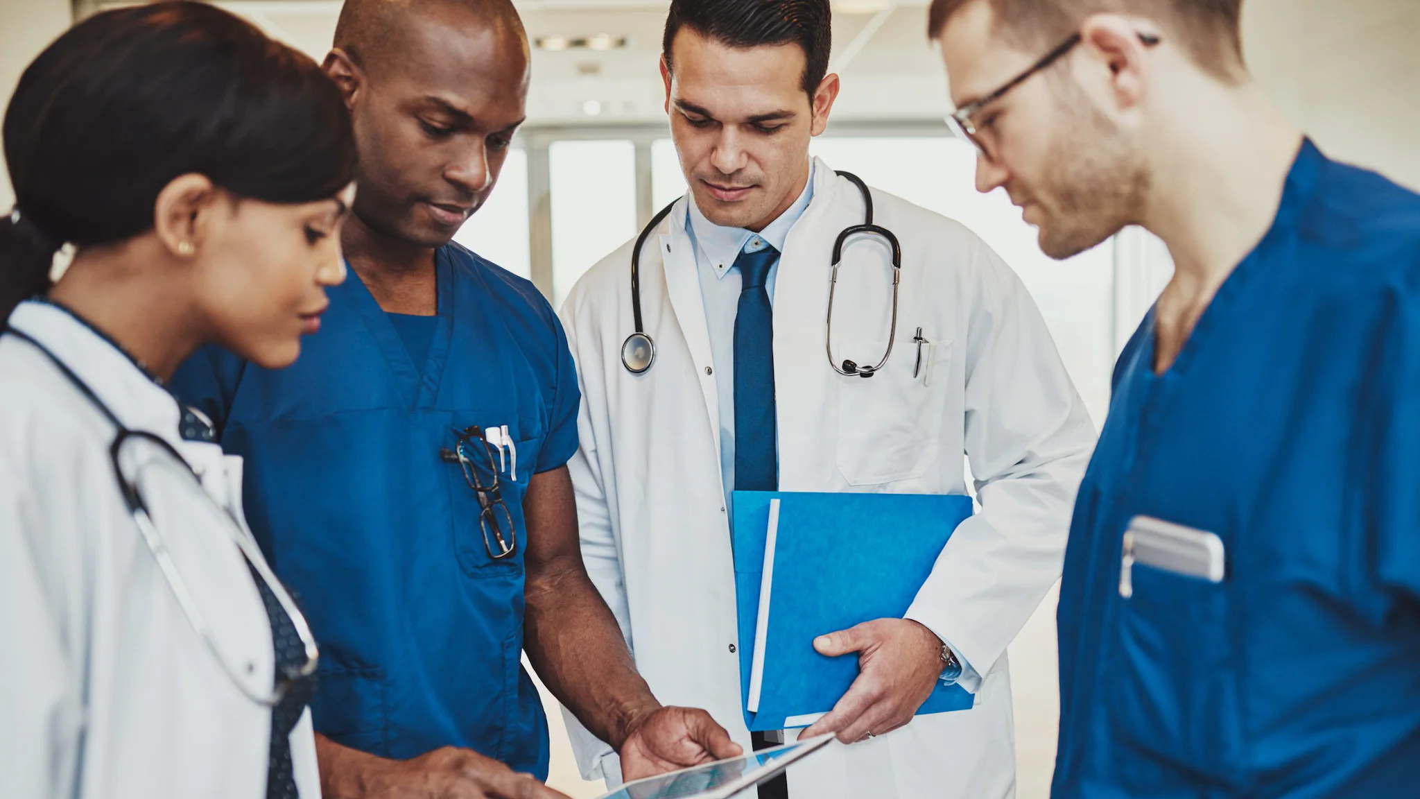 Healthcare providers huddle together and look down at a tablet