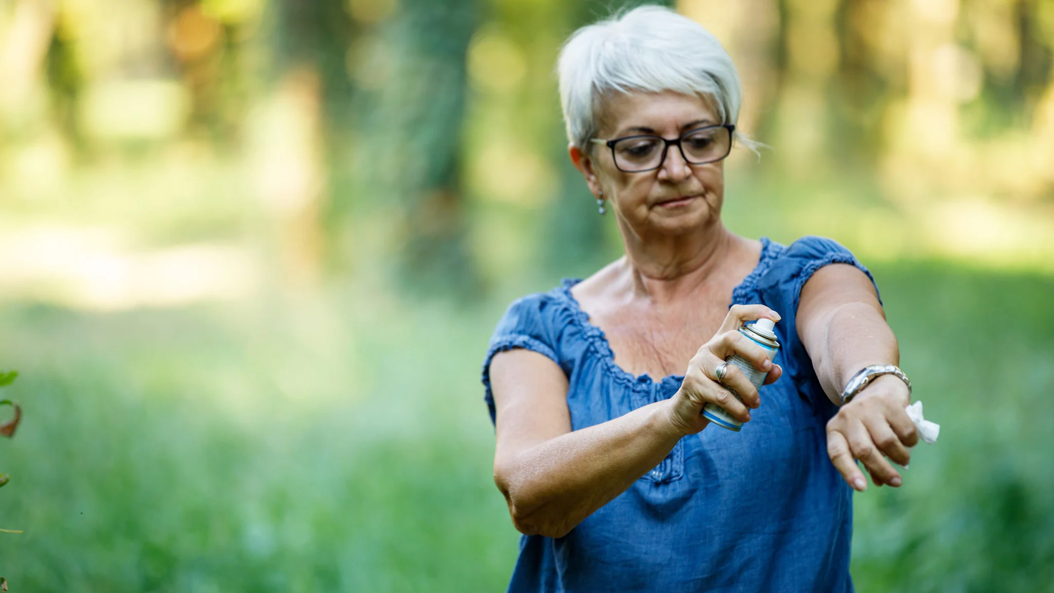 Woman spraying insect repellent on her arm