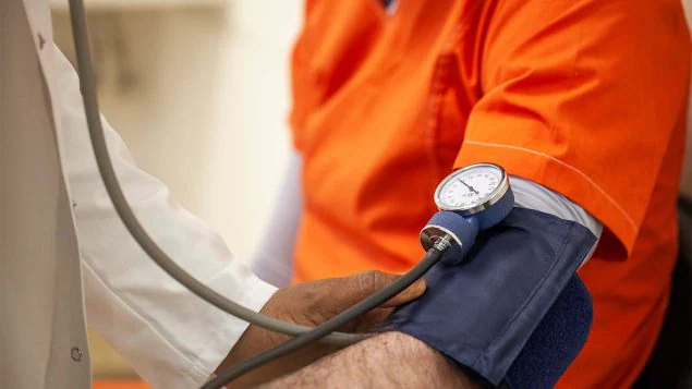 The figure is a photo of a health care provider checking a person’s blood pressure.