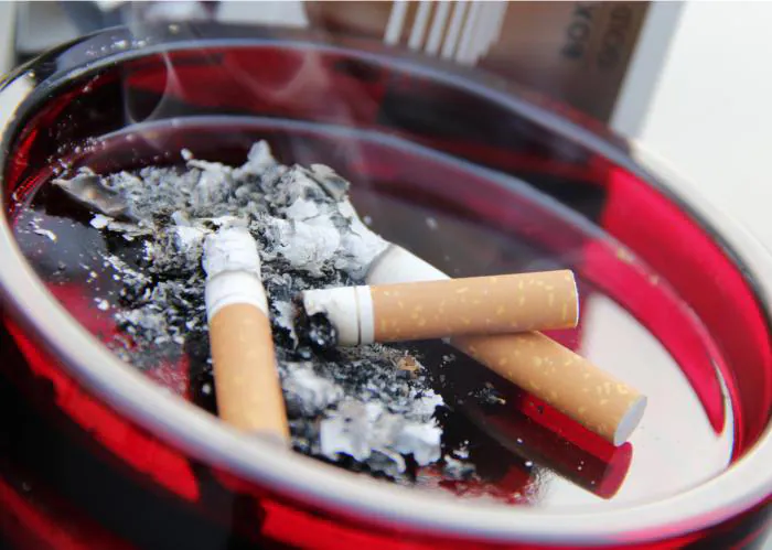 phapproach03 A bright red ashtray filled with smoldering cigarettes and ashes.