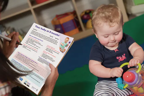 Mom using milestone checklist while baby plays