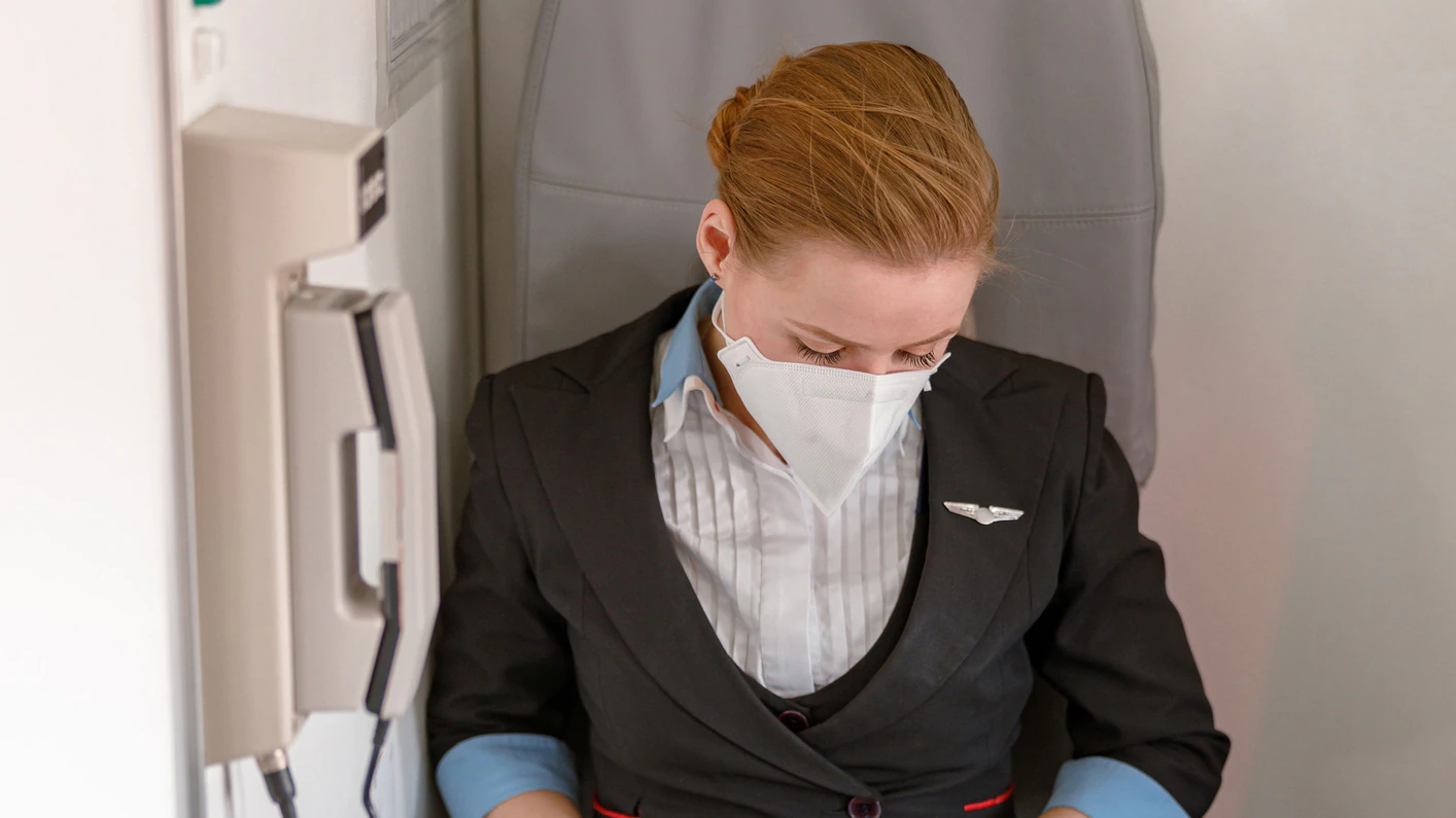 Female aircrew member seated aboard a commercial aircraft.