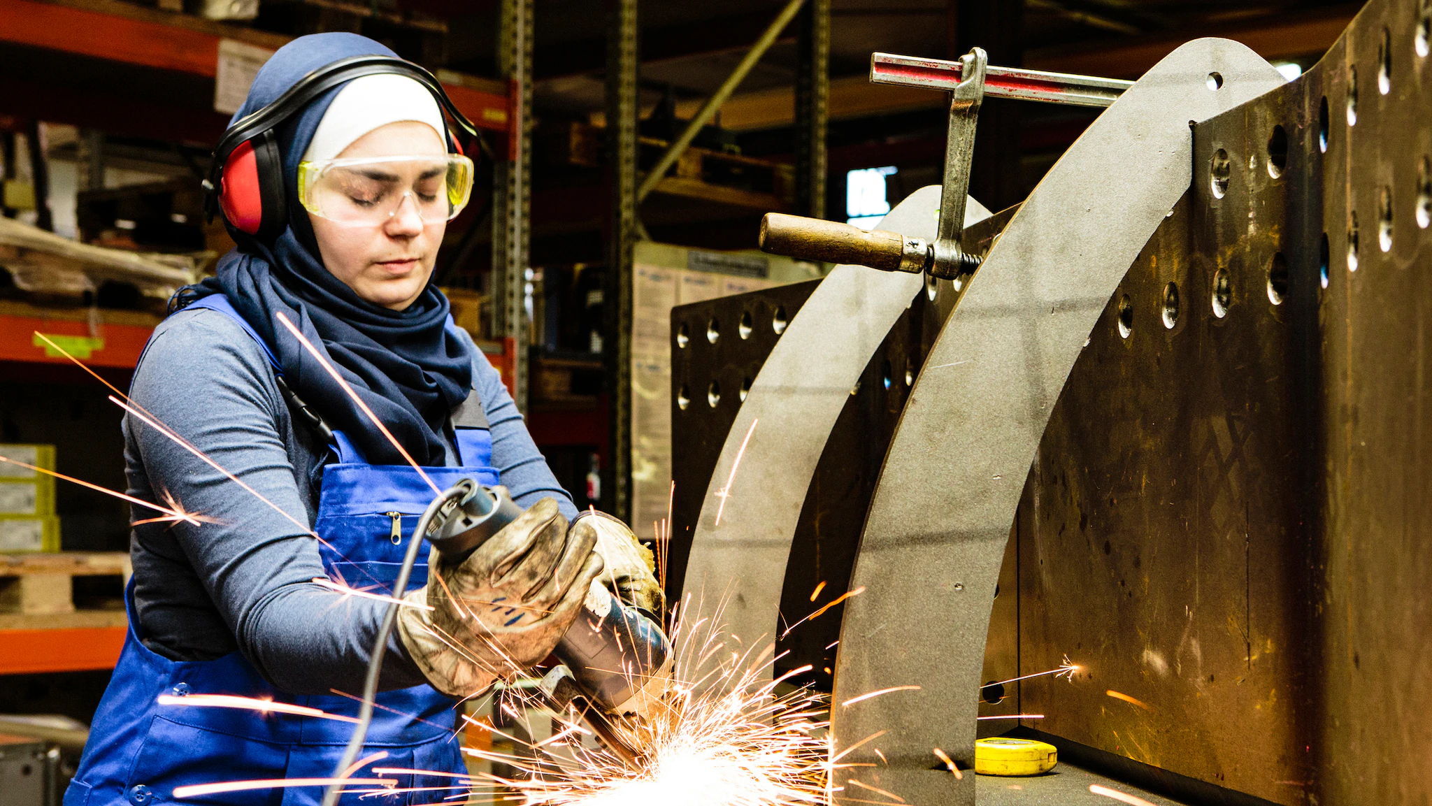 A female worker in PPE is shown working in an industrial setting.