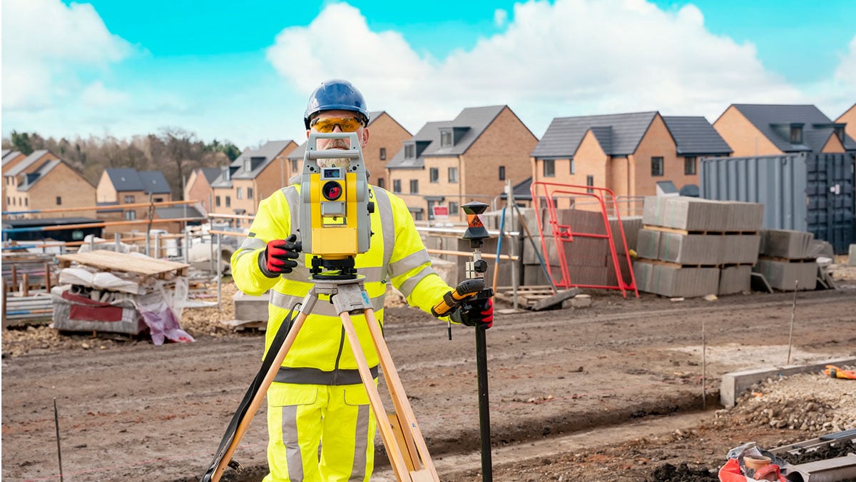 Male construction worker wearing PPE doing surveying on a construction site