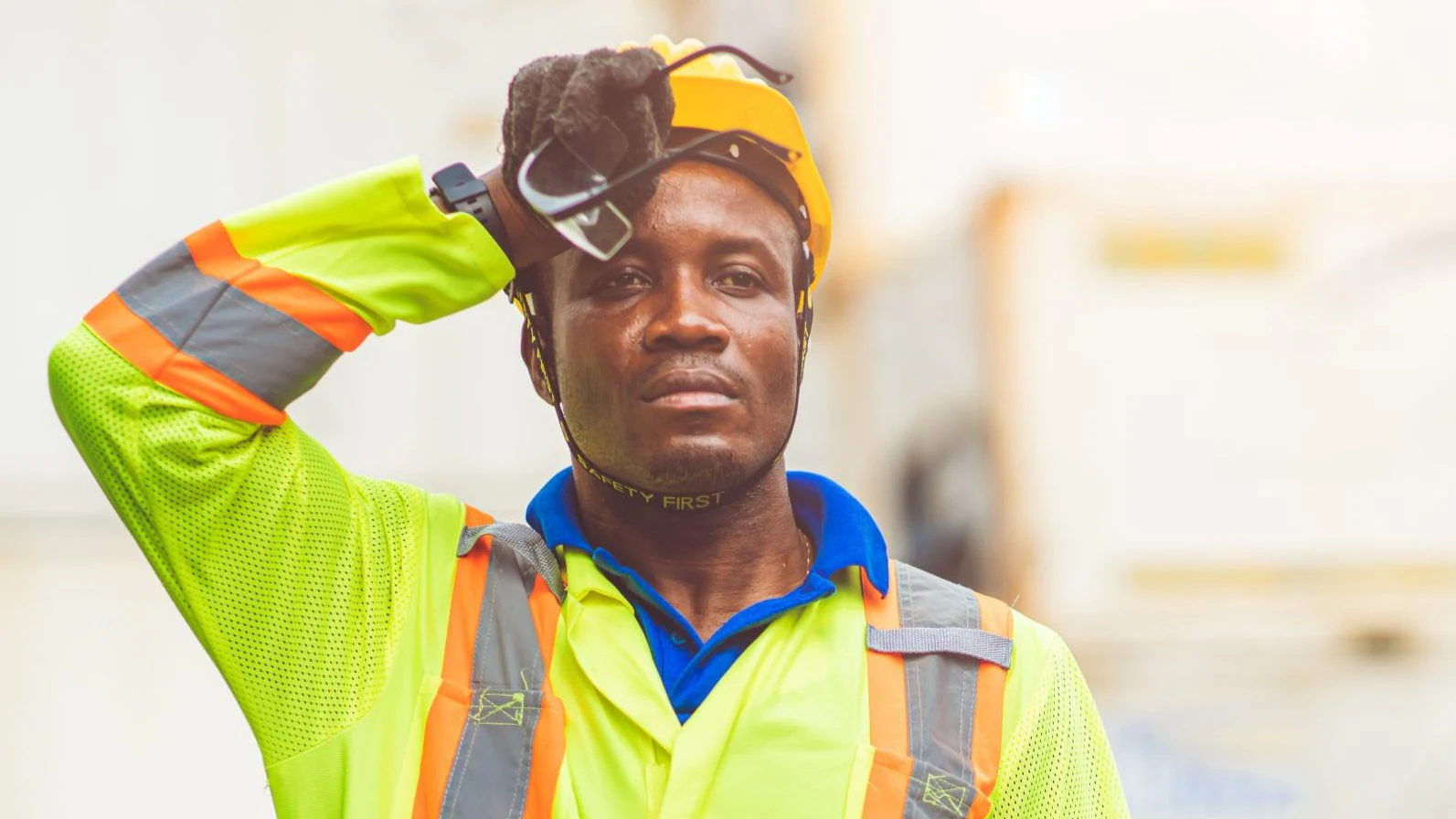 A construction worker wipes his brow while working outside on a hot day.