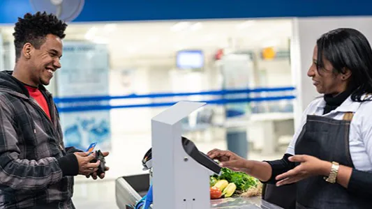 Man at grocery store checkout with fruit and vegetables.