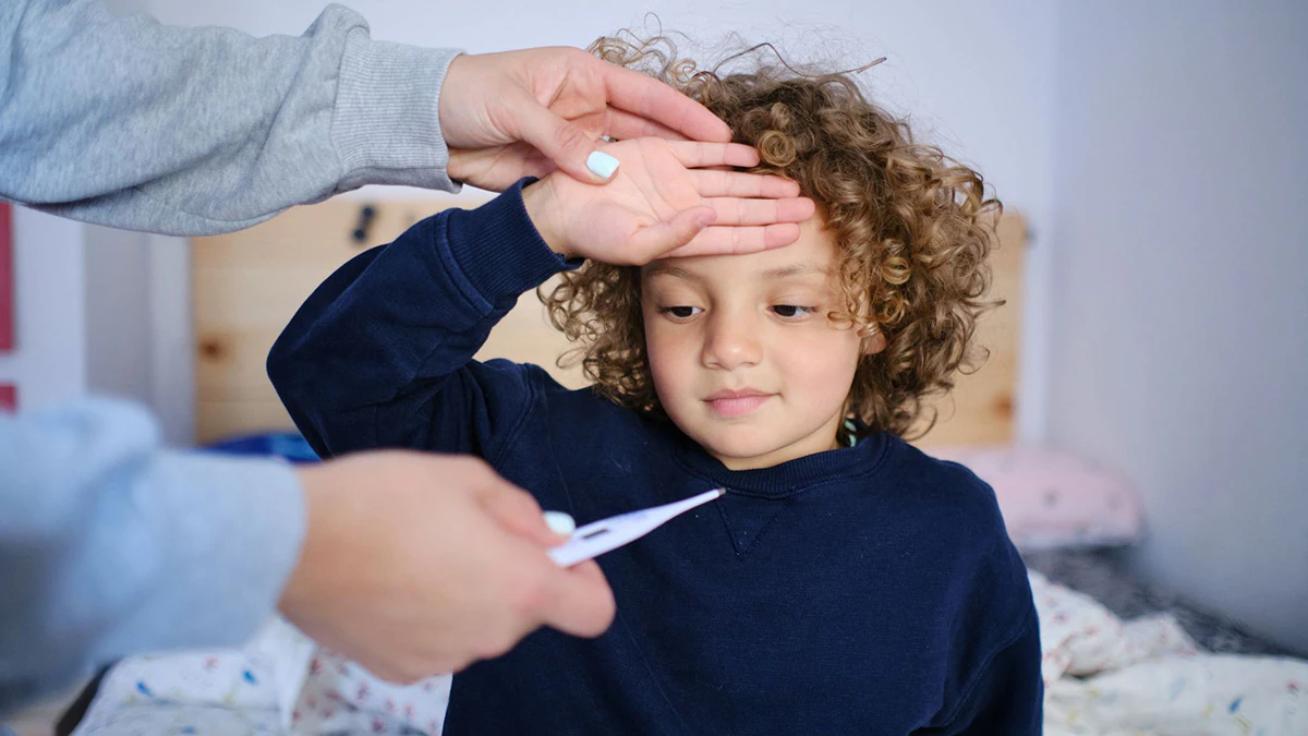 Mother takes the temperature of her child with fever symptoms