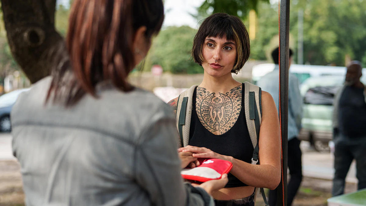 A woman with a large tattoo interacts with a syringe services provider.