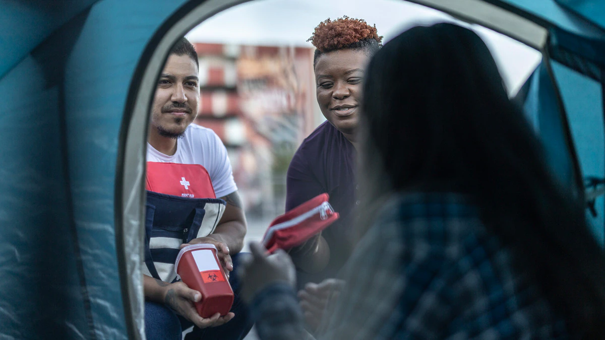 Aid workers help an unhoused person.