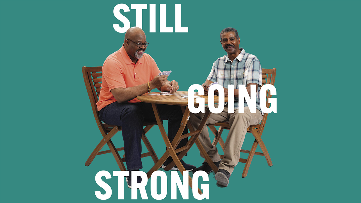 Two older men sitting at a table playing a game of cards.