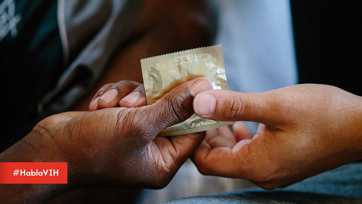 Two male hands holding a condom. #HablaVIH