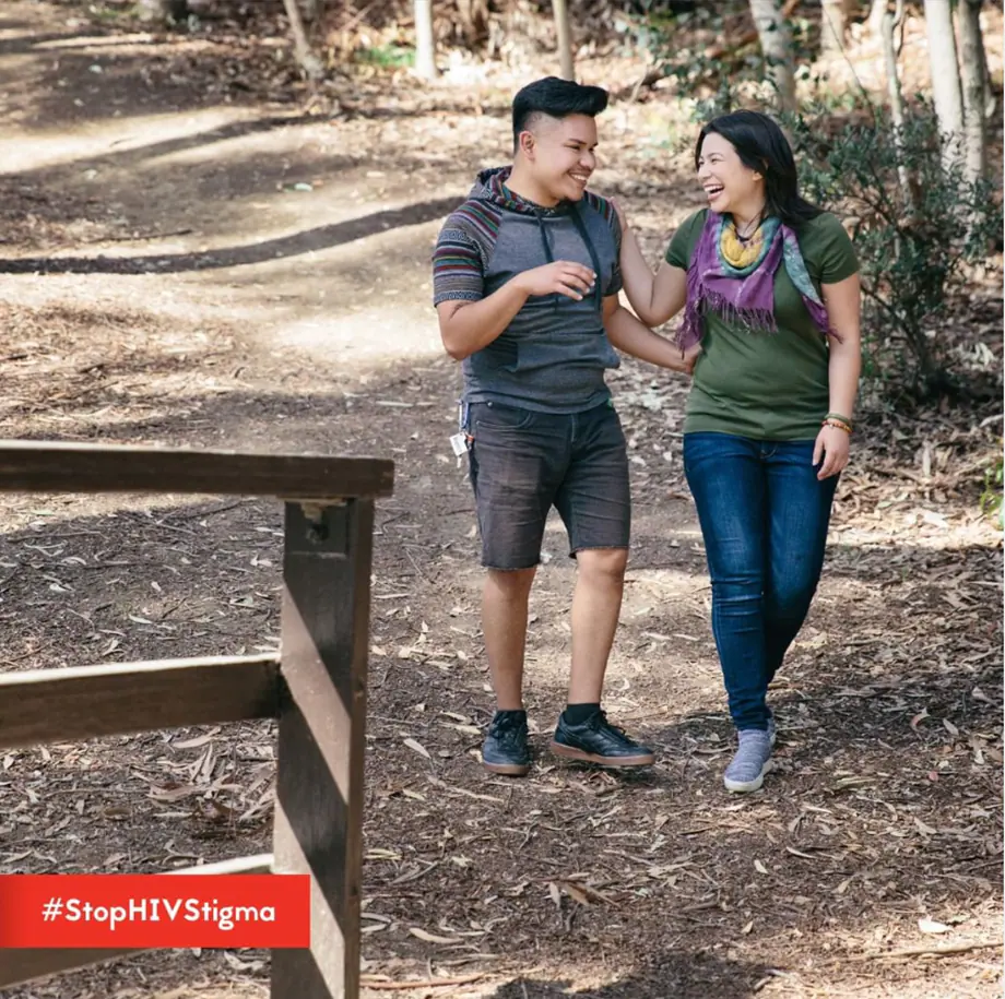 Image displays a man and woman laughing and smiling at each other while walking in the woods.