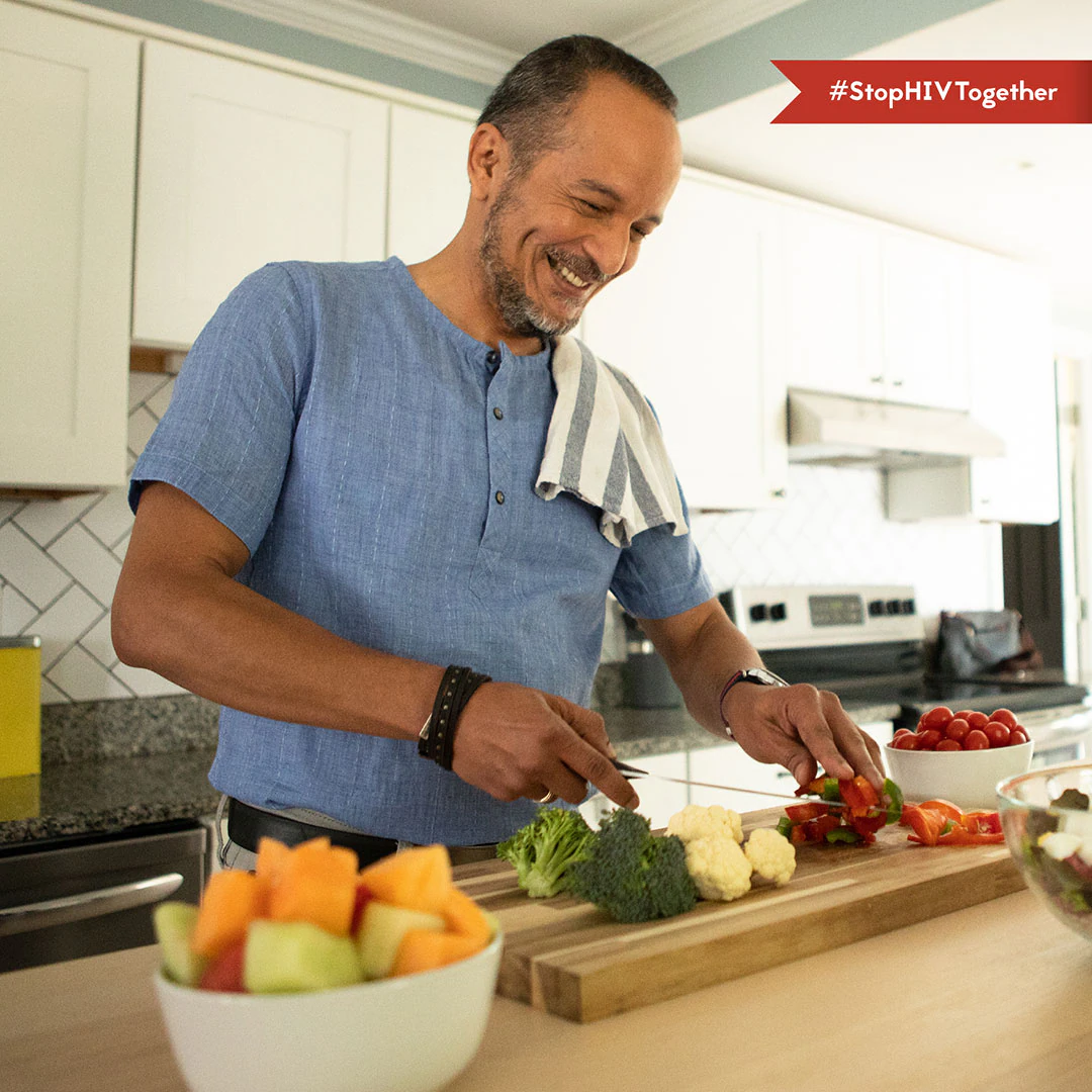 An image of a man chopping vegetables in his kitchen.