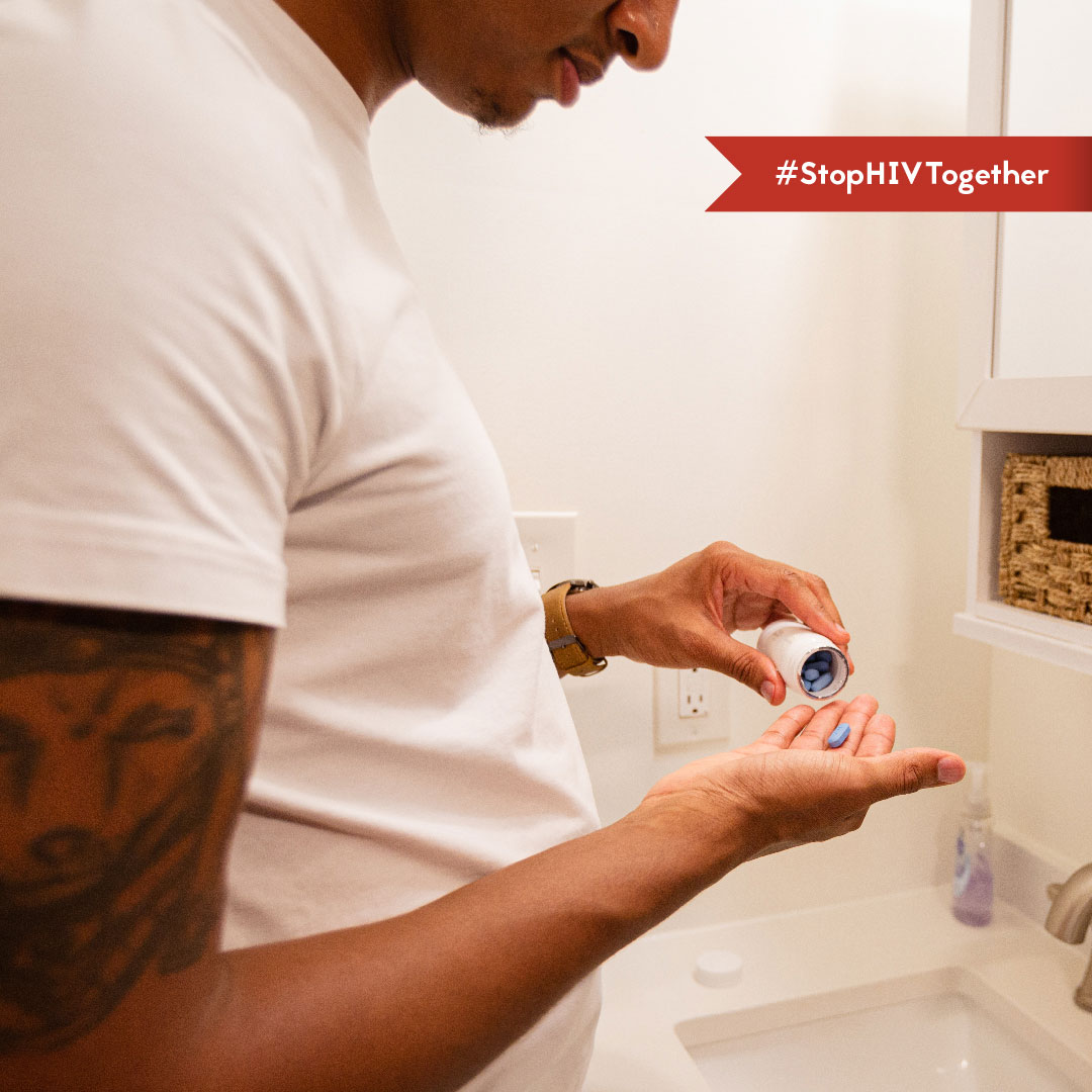 An image of a man taking a PrEP pill in his bathroom.