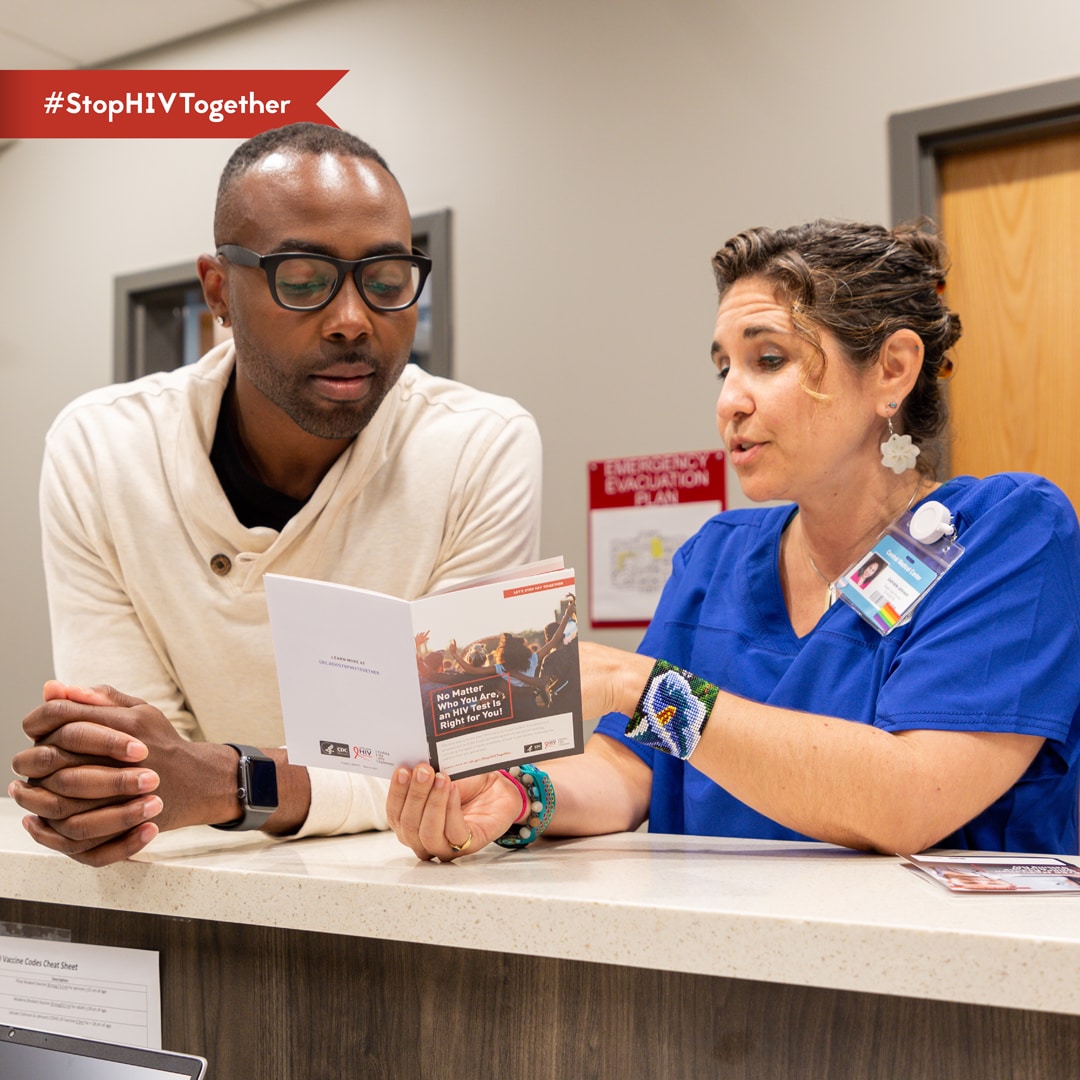 An image of a provider conversing with a patient and reading from a pamphlet.