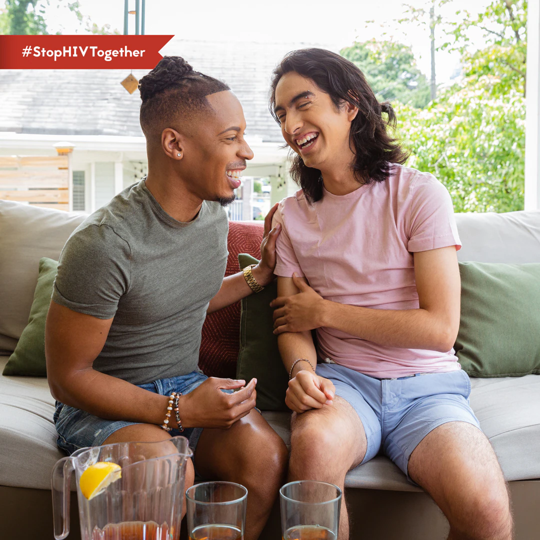 An image of two male friends laughing together while sitting on a patio.