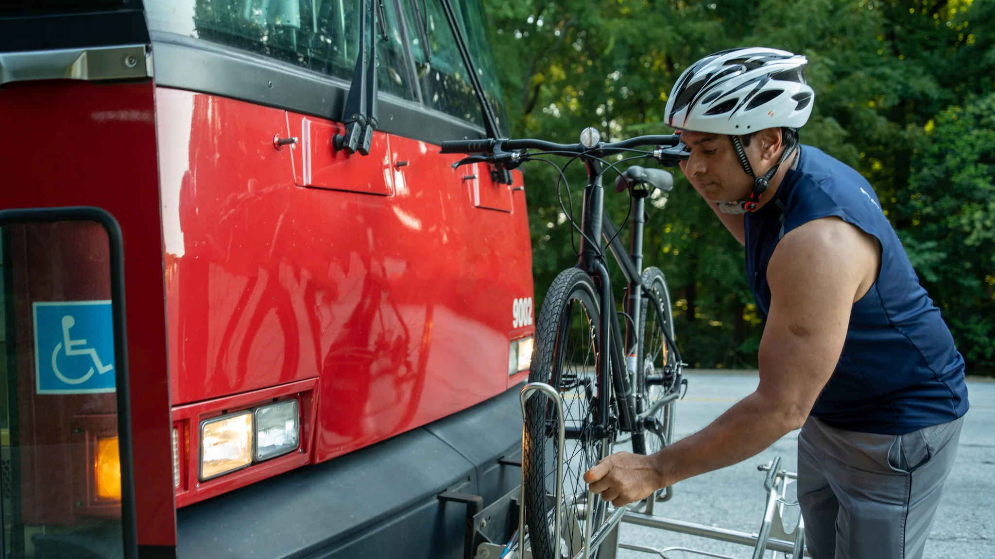 Man putting a bike on the front of a bus.