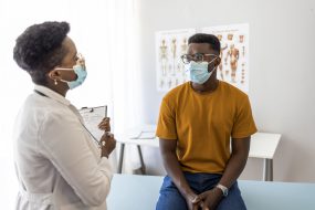 A young man listens to a healthcare provider at a clinic.