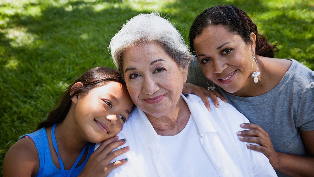 Three generations of women look and smile at camera