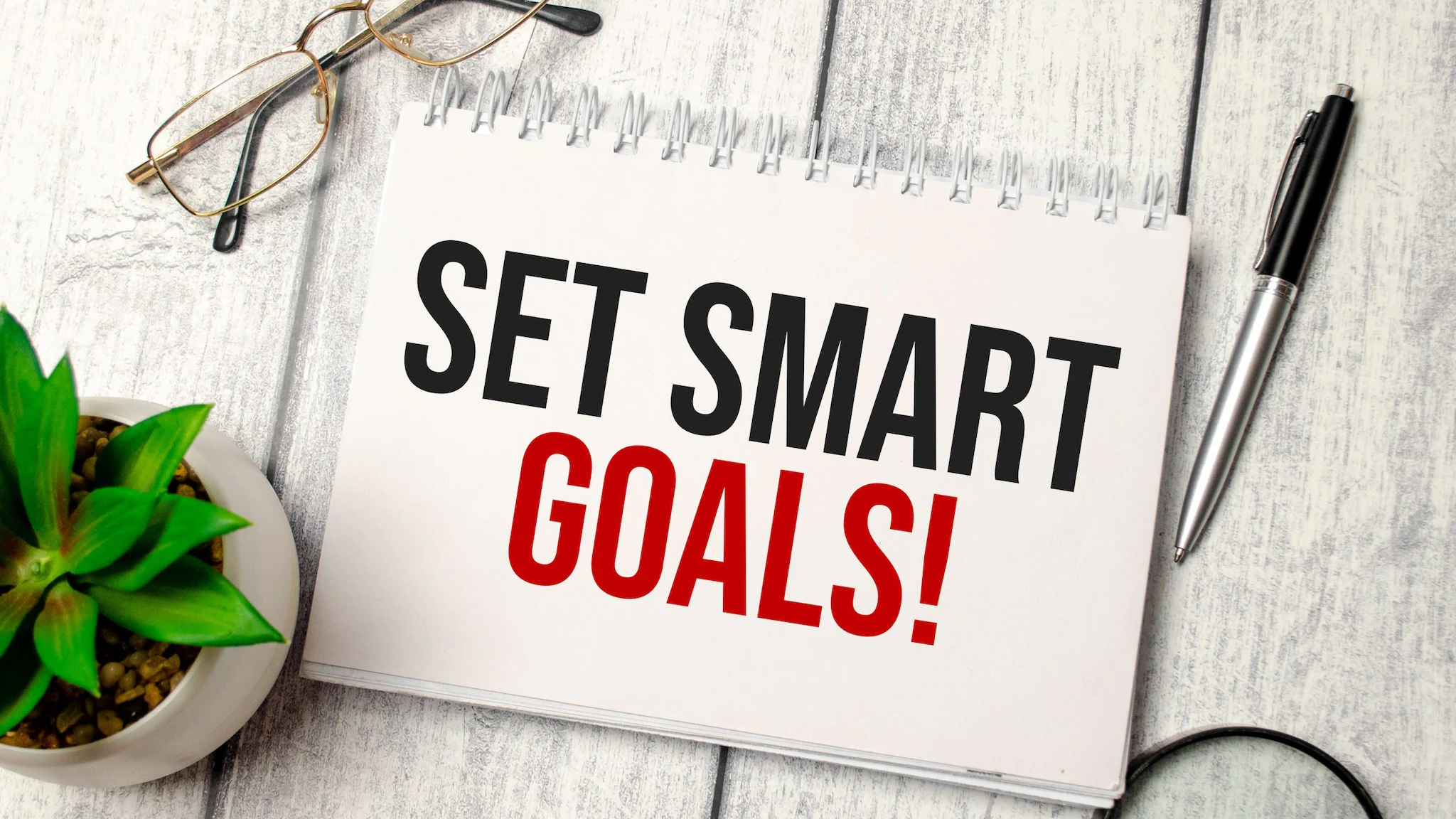 A spiral notebook with text that reads, "Set SMART goals."